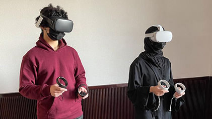 A male and a female student wearing virtual reality goggles and holding VR sticks